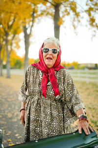 Thumbnail for Woman wearing a red headscarf and sunglasses outdoors with trees in the background