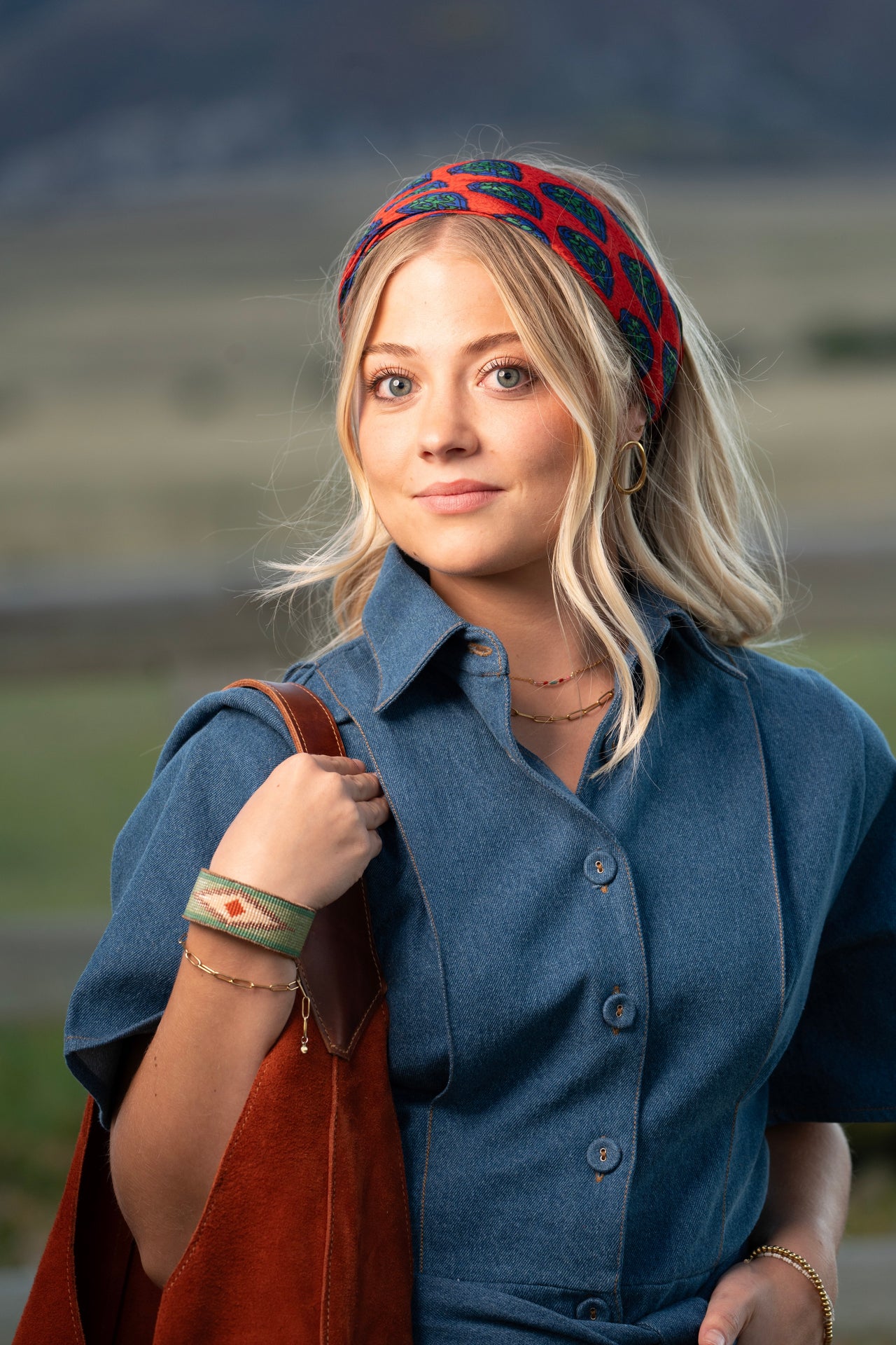 Woman wearing a fairtrade blue outfit and red headband with a blurred natural background