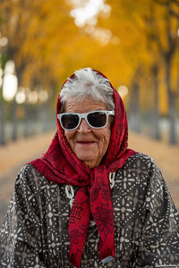 Thumbnail for woman wearing a red headscarf and sunglasses with a blurred autumn background